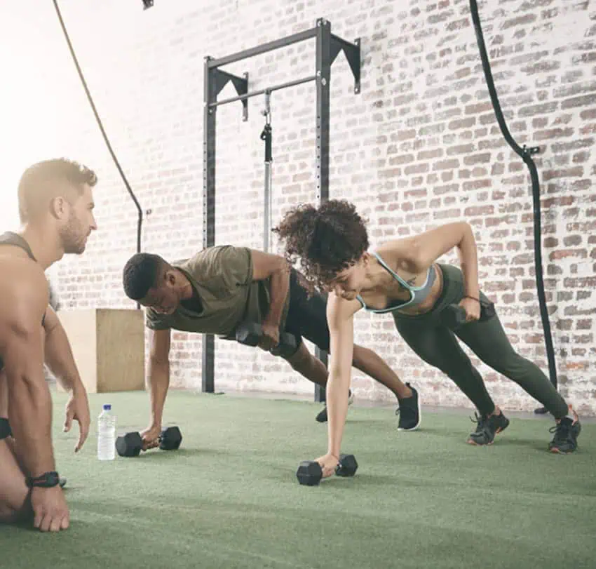 Personal trainer with two clients lifting weights